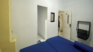 A room with a bed, a mirror, a door, and a small table. - OYO 95038 Khanza Stay (Semarang)