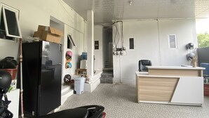 A room with a desk, a black refrigerator, a water dispenser, and a small seating area. - OYO 95038 Khanza Stay (Semarang)