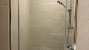 A glass-enclosed shower with a handheld showerhead and a wall-mounted faucet. - Vesta - Luxury Studio - Riviera (Dubai)
