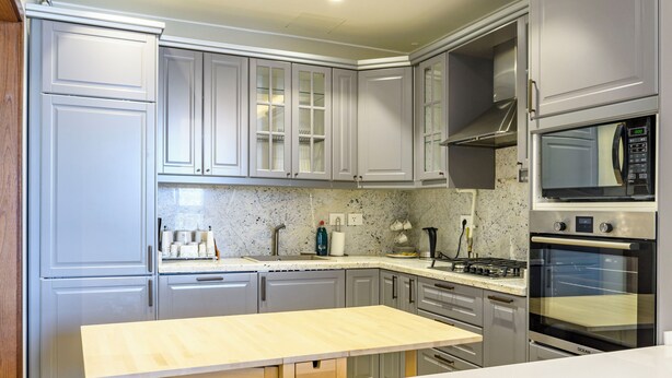 A modern kitchen with grey cabinets, stainless steel appliances, and a wooden countertop. - Vesta - Luxury Apt- 1br- Aeon Tower (6th of October City)