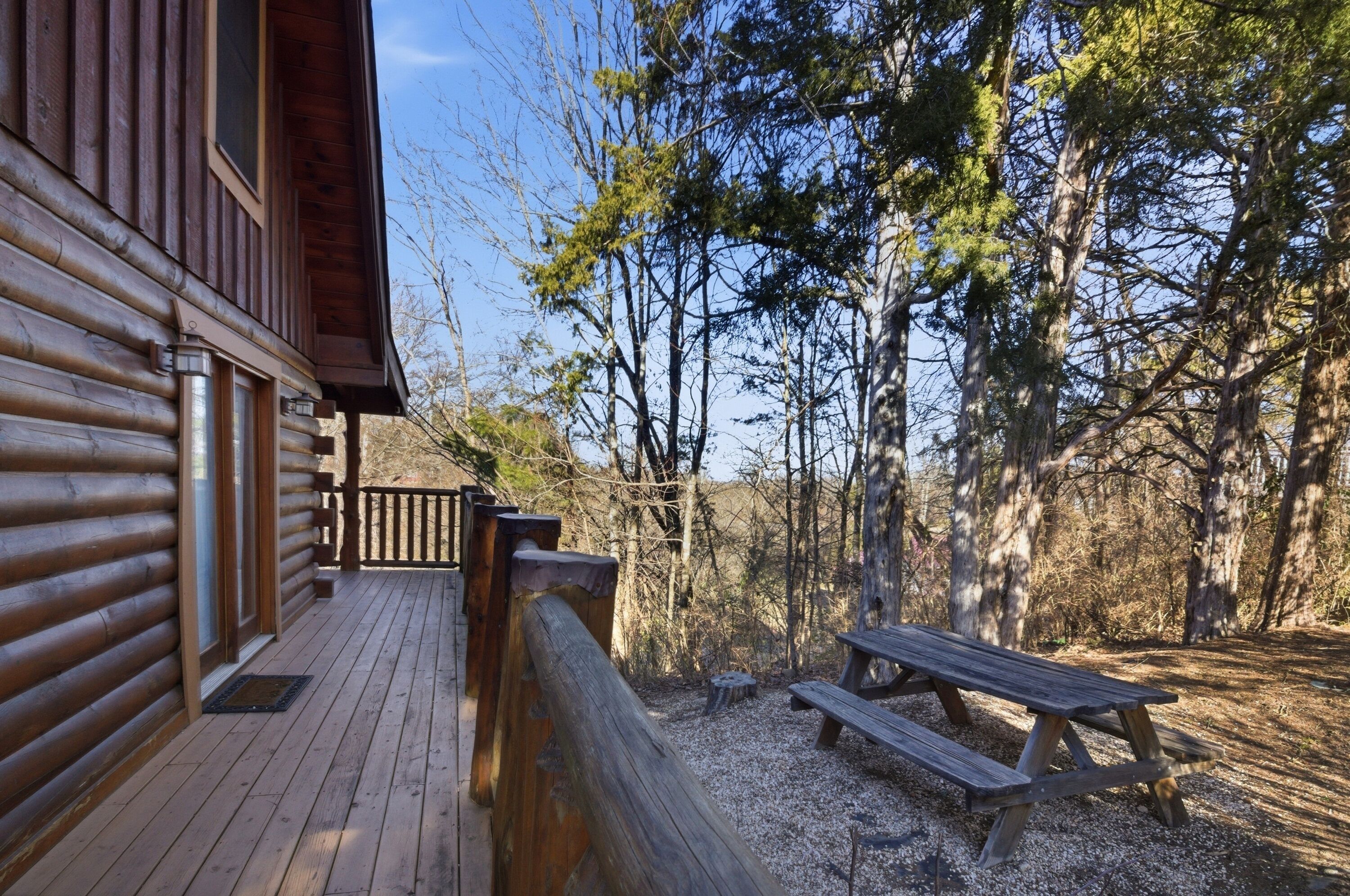 A wooden cabin with a deck and a picnic table.