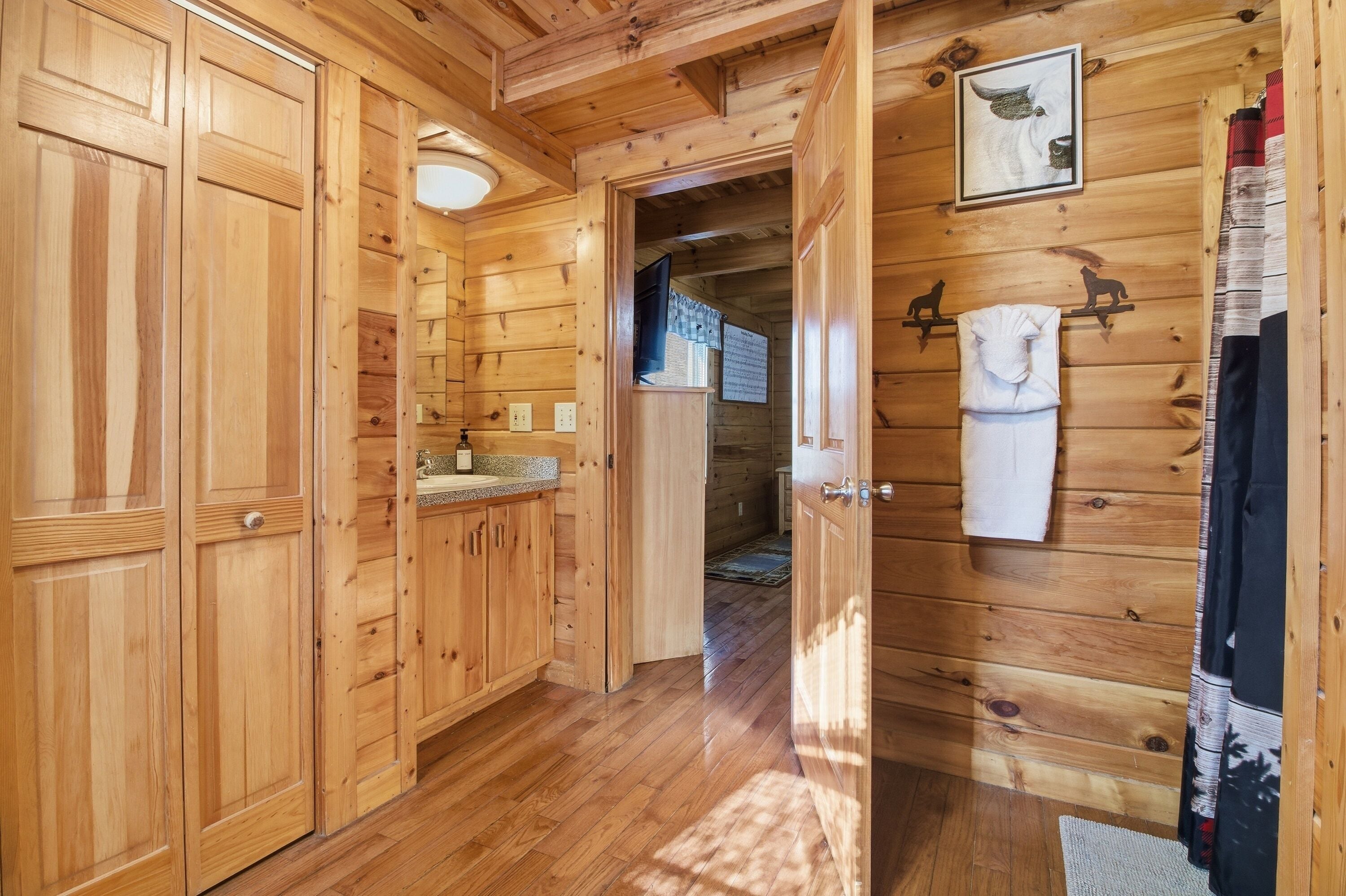 A wooden interior with a kitchen area, wooden cabinets, and a hallway leading to another room.