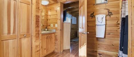 A wooden interior with a kitchen area, wooden cabinets, and a hallway leading to another room.