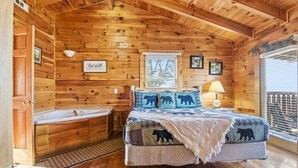 Un dormitorio de cabaña de madera con una cama grande, una bañera de madera y una ventana con persianas.