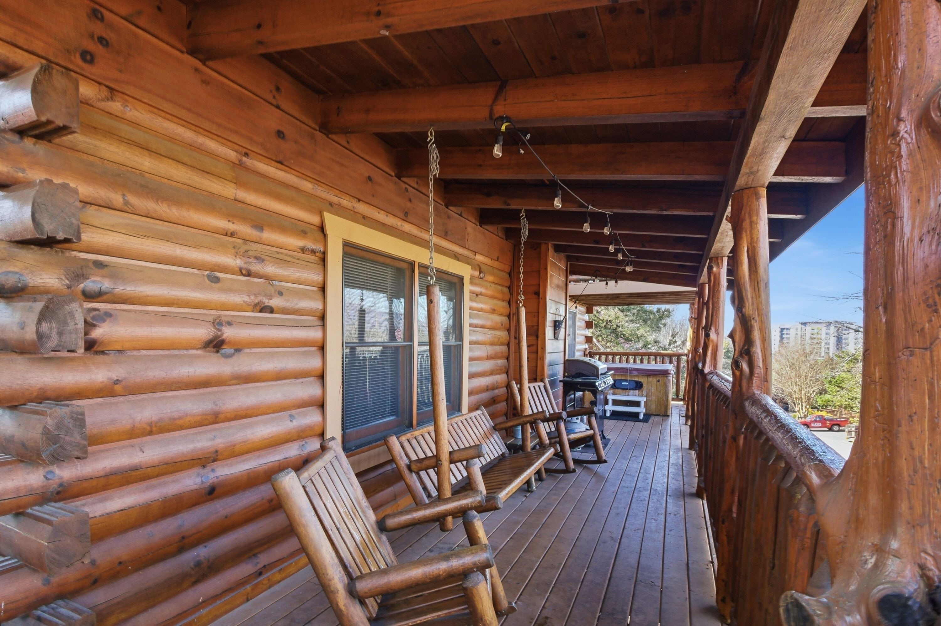 A wooden cabin with a porch featuring benches and a grill area.
