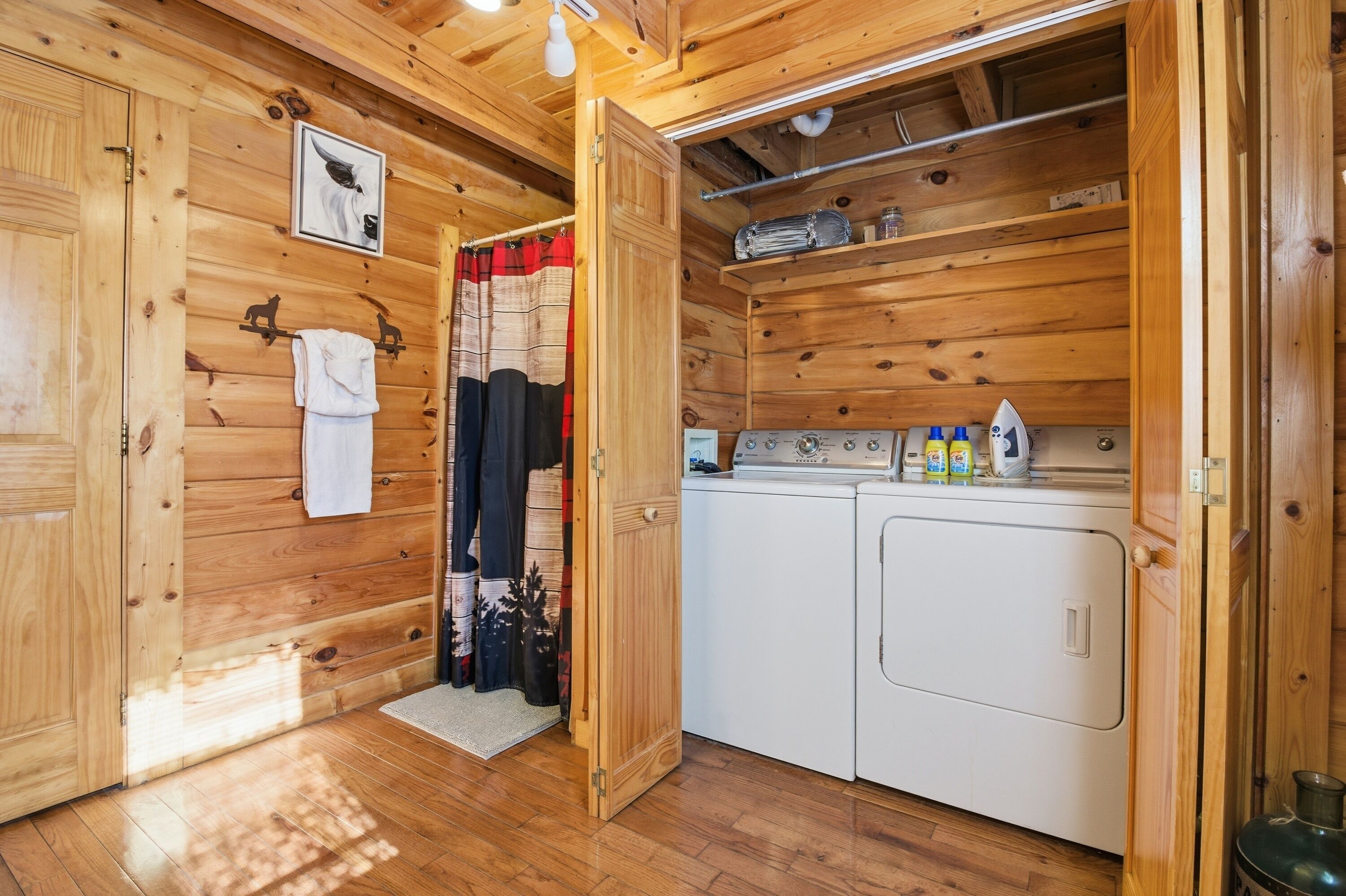 Ein Holzhütten-Innenraum mit Waschmaschine, Wäscheständer und einem Handtuch an der Wand.