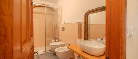 Une salle de bain moderne avec une douche à parois de verre, un lavabo blanc et un grand miroir.