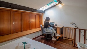 A room with wooden flooring, a desk with a computer, a chair, and a bed with towels. - Gemma Apartment with AC Sea View Balcony (Vernazza)