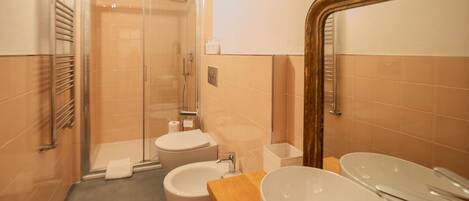 Ein modernes Badezimmer mit einer Duschkabine, einer Toilette, einem Waschbecken und einem Spiegel.