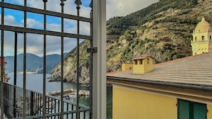 A coastal view with a balcony, a yellow building, and a bell tower. - Gemma Apartment with AC Sea View Balcony (Vernazza)