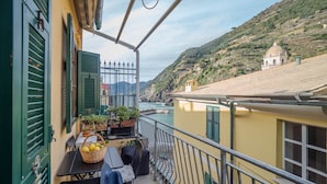 A balcony with a table, chairs, and potted plants. - Gemma Apartment with AC Sea View Balcony (Vernazza)
