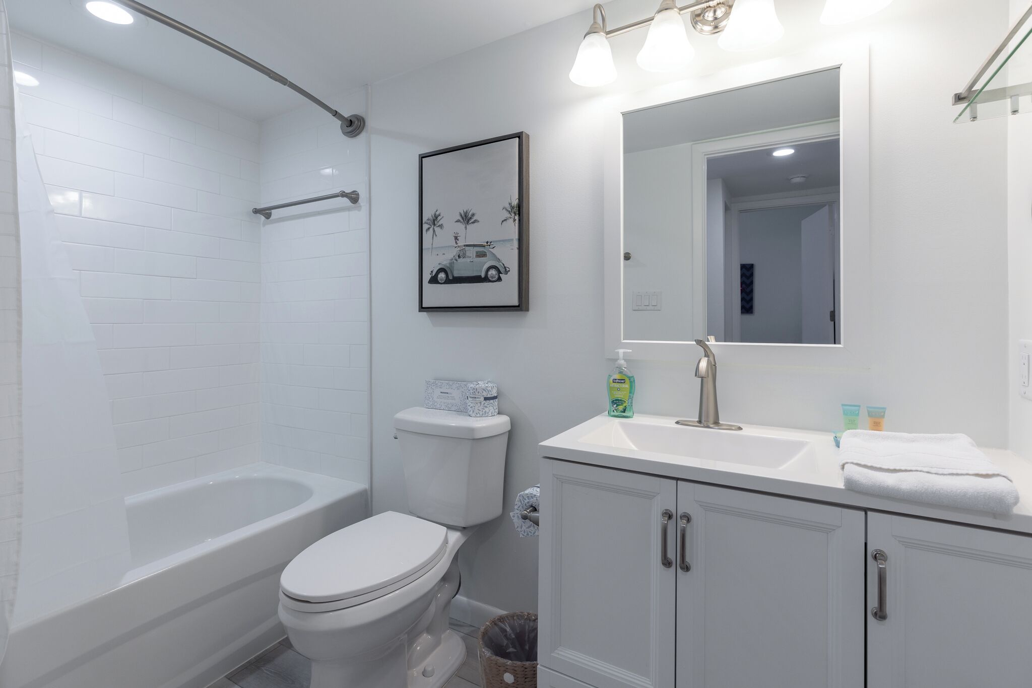 A modern bathroom with a bathtub, toilet, and vanity with a mirror.