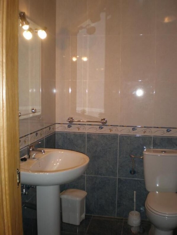 Een badkamer met een wastafel, toilet en spiegel.