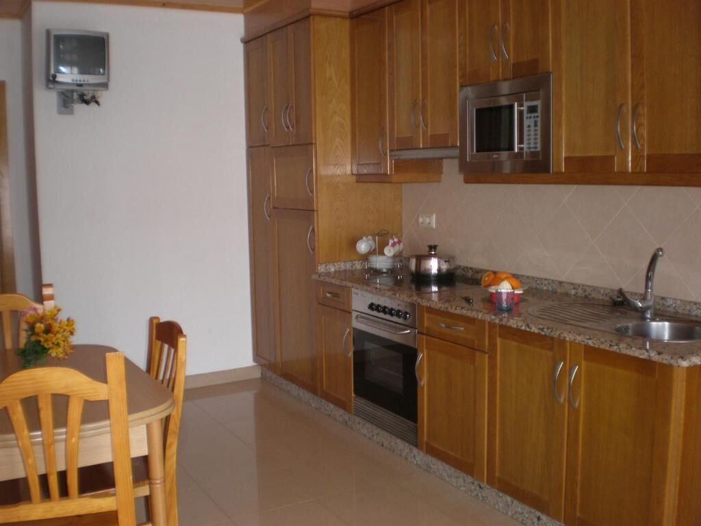 A kitchen with wooden cabinets, a microwave, an oven, and a sink.
