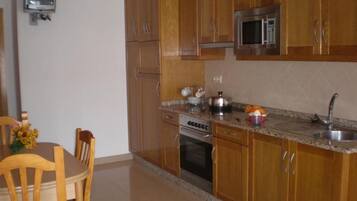 A kitchen with wooden cabinets, a microwave, an oven, and a sink.