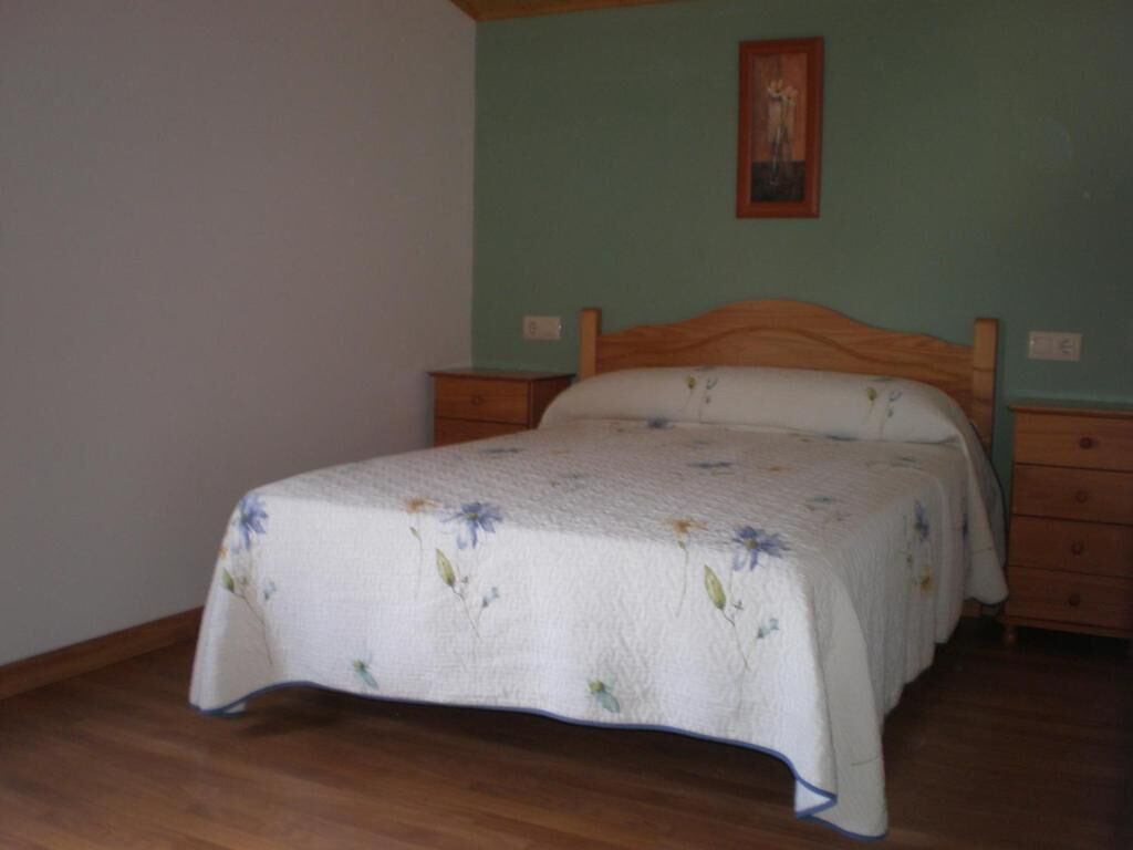 Ein Schlafzimmer mit einem hölzernen Bett, einem Nachttisch und einer Kommode.