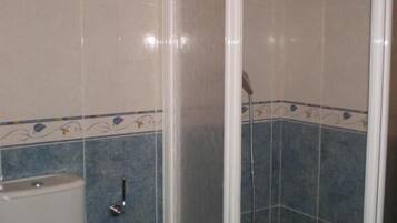 Un baño con inodoro, cabina de ducha y paredes con azulejos azules.