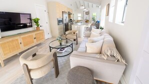 Un salon moderne avec un canapé, des fauteuils, une table basse et un téléviseur.