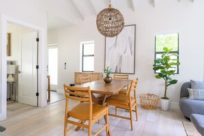 A dining area with a wooden table and chairs, a hanging light fixture, and a large window with a view of greenery. - Multi Family Resort Like Getaway: Casa Lucia (Miami)
