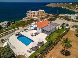 A modern villa with a swimming pool, a covered patio, and a view of the sea. - Villa Hemera (Chania)