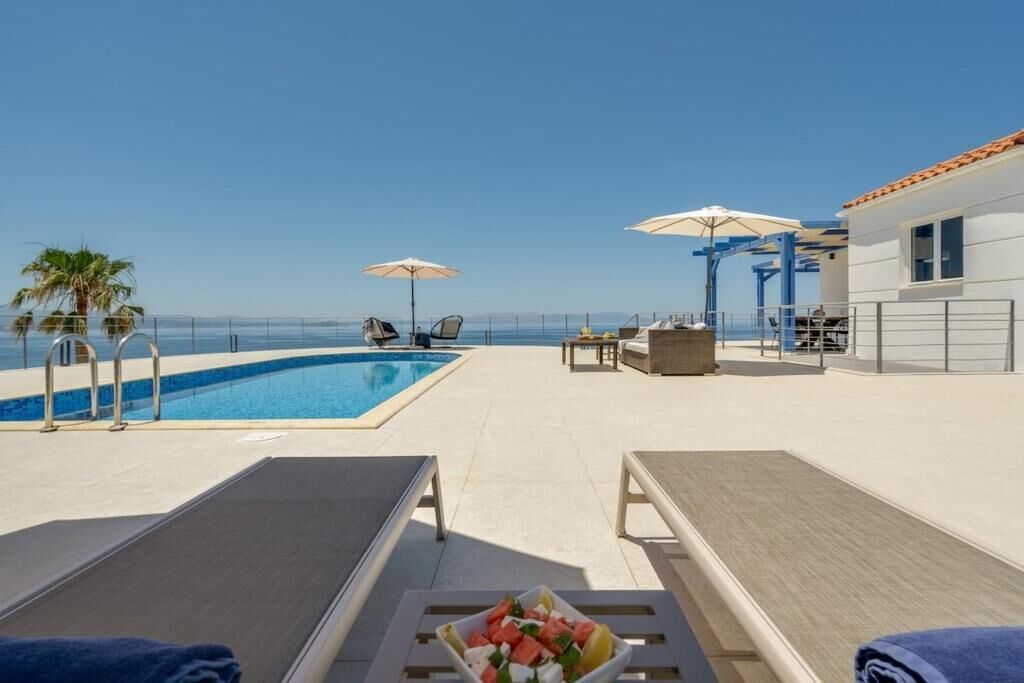A poolside area with lounge chairs, umbrellas, and a table with a fruit bowl.