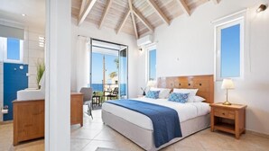 A bedroom with a large bed, a nightstand, a desk, and a view of the outdoors. - Villa Hemera (Chania)