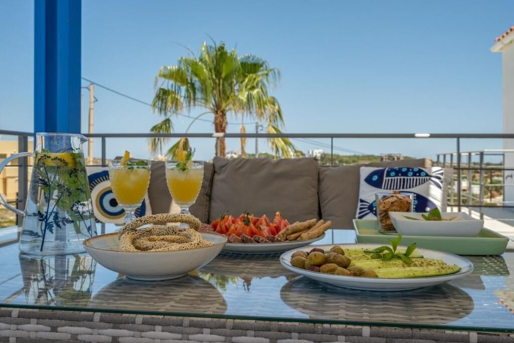 Une table avec de la nourriture et des boissons, un canapé et une vue sur des palmiers et un immeuble.