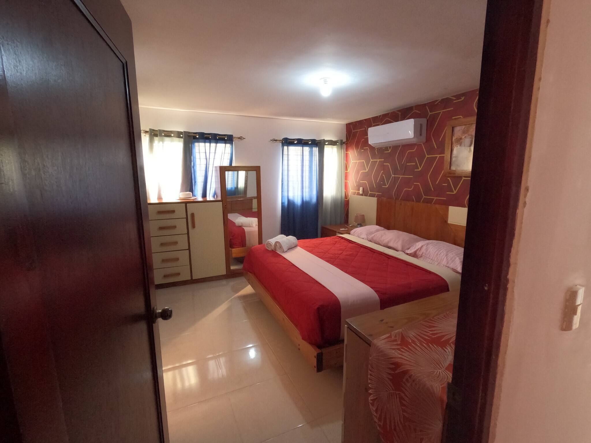 Ein Schlafzimmer mit einem Bett, einem Kleiderschrank, einem Spiegel und einer Wandklimaanlage.