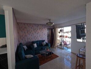 A modern living room with a sofa, a coffee table, and a TV. - Charming 2-bedroom Apartment With Stunning Views in Santiago (Santiago de los Caballeros)