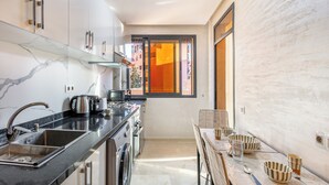 Une cuisine moderne avec un pare-feu en marbre, des appareils en acier inoxydable et un coin repas comprenant une table et des chaises.
