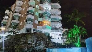 Un hôtel à plusieurs étages doté de balcons, d’une piscine et d’une formation rocheuse en premier plan.