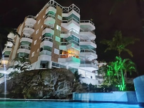 Ein mehrstöckiges Hotel mit Balkonen, einem Pool und einer Felsformation im Vordergrund.