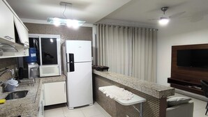 Une cuisine moderne équipée d’un réfrigérateur, d’un four à micro-ondes et d’une cuisinière intégrés. Un petit coin salon avec un téléviseur et un ventilateur de plafond est également disponible.