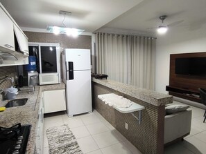Eine moderne Küche mit integriertem Kühlschrank, Mikrowelle und Herd. Ein kleiner Sitzbereich mit Fernseher und Deckenventilator.