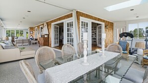 En rummelig opholdsstue med et glasbord, fletningsmøbler og udsigt til det fri.