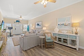 A living room with a sofa, a chair, a small table, a cabinet, and ceiling fans. - Private House, pet friendly, 0.3 miles from beach + Free Attraction Tickets! (North Myrtle Beach)