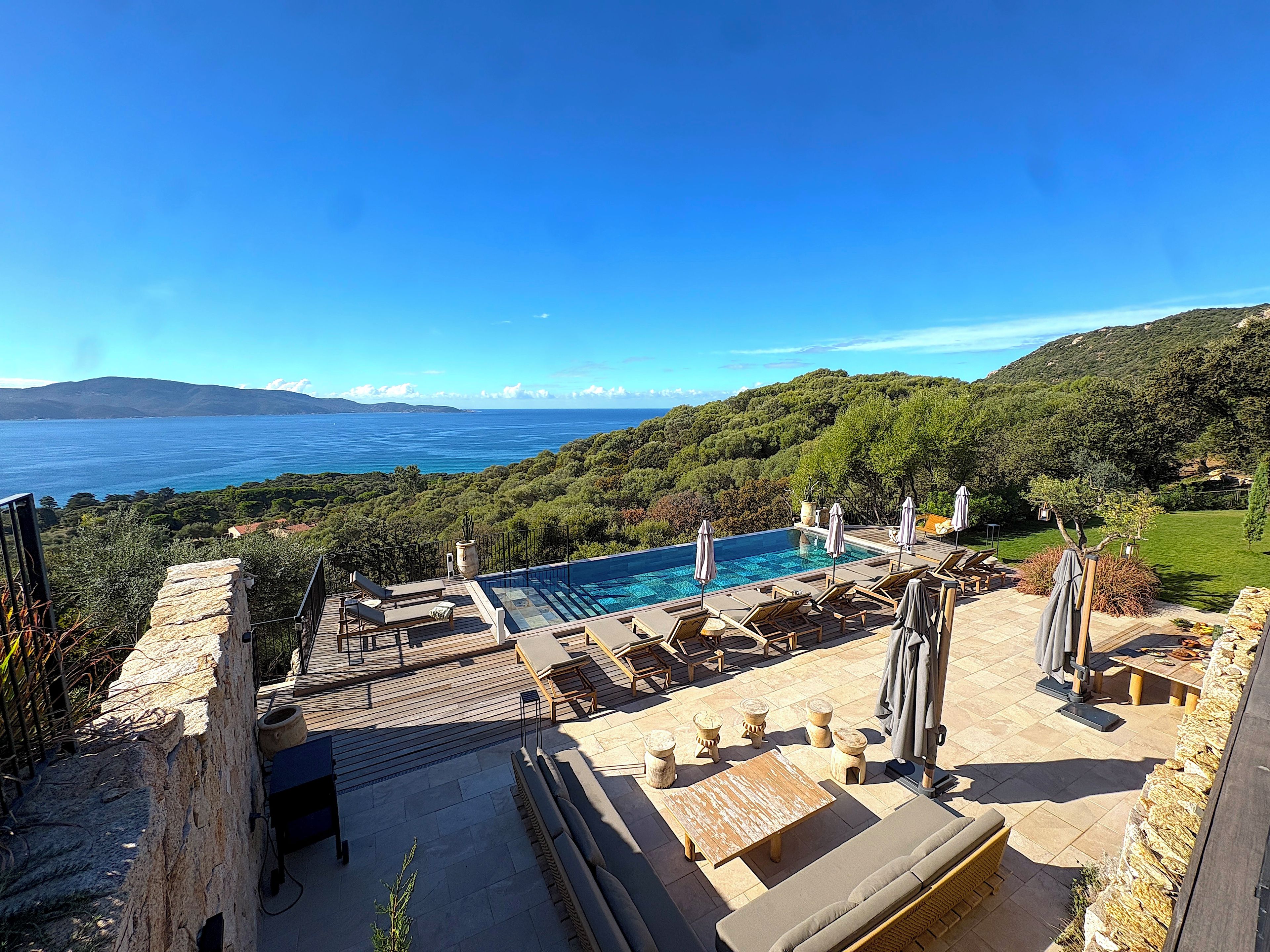 Un espace aménagé au bord de la piscine, avec des chaises longues et une vue sur la mer.