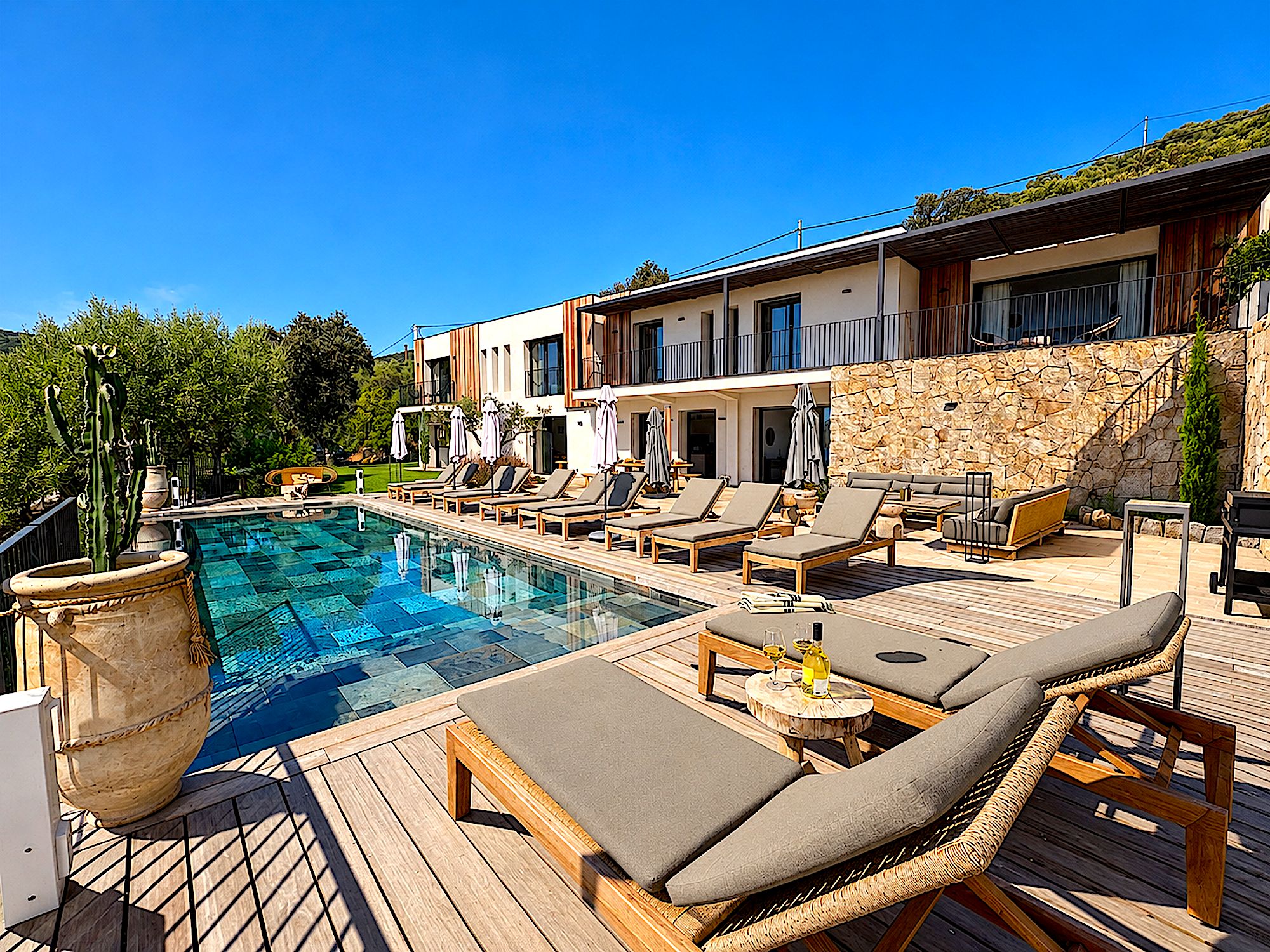 A poolside area with lounge chairs and a stone wall.
