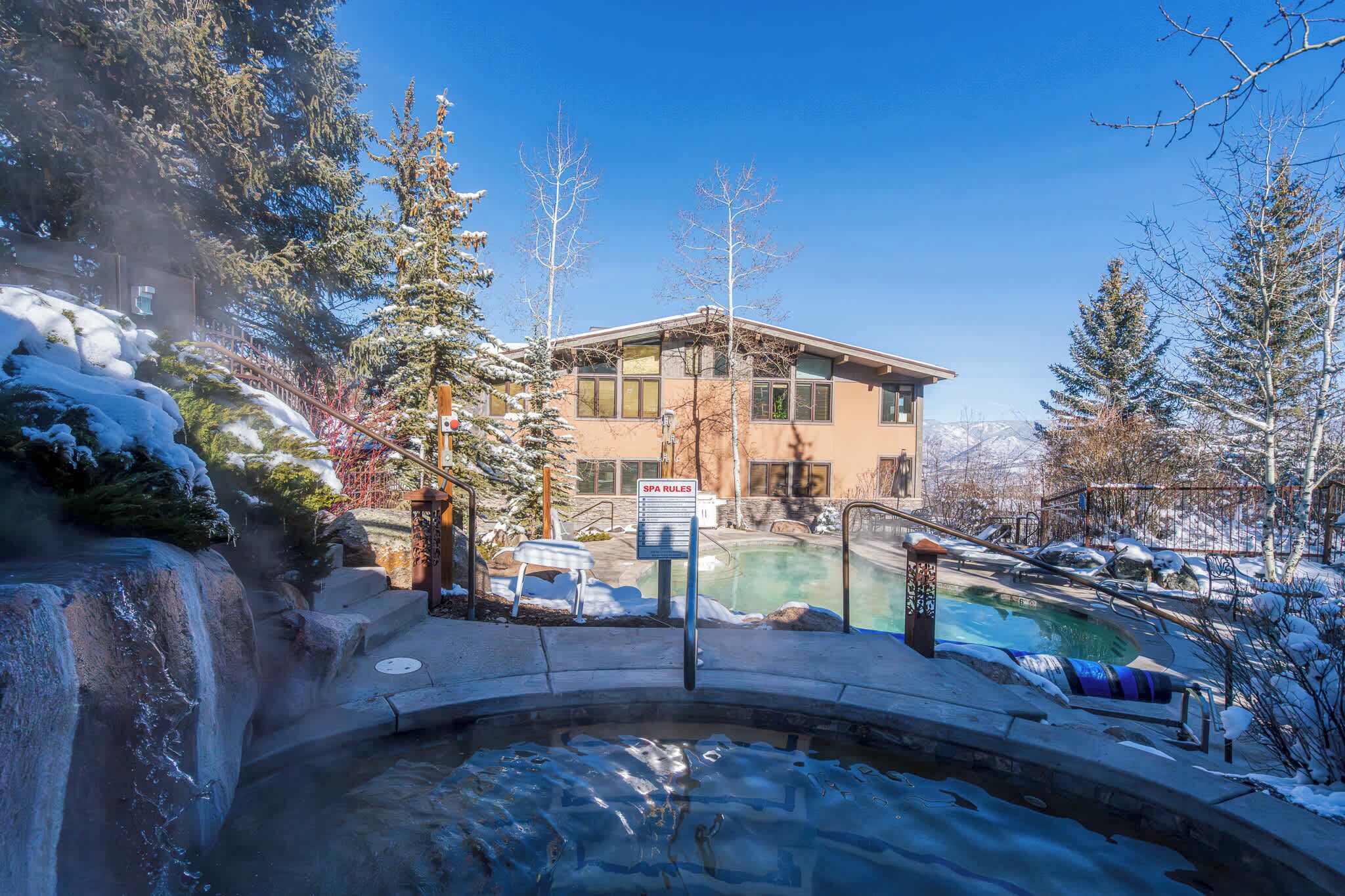 A spa area with a hot tub, a pool, and a building with a sign reading "SPA RULES". - New Ski-in Ski-out 1 BR with Resort Amenities (Snowmass Village)