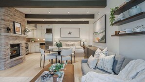 A modern living room with a fireplace, a dining area, and a sofa set. - New Ski-in Ski-out 1 BR with Resort Amenities (Snowmass Village)