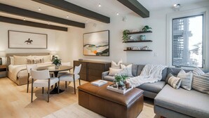 A modern living room with a sofa, coffee table, and dining area. - New Ski-in Ski-out 1 BR with Resort Amenities (Snowmass Village)