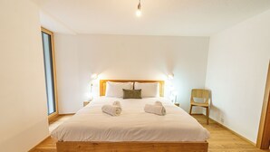 Una camera da letto con un letto di legno, due cuscini, una sedia e un comodino.