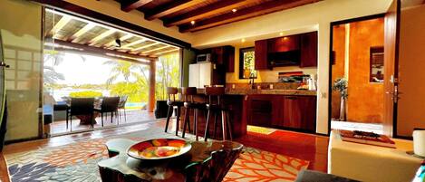 A spacious living area with a dining table, kitchen, and large sliding glass doors leading to a balcony with a view.