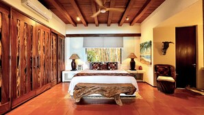 A bedroom with a bed, wooden wardrobe, bedside lamps, a chair, and a painting on the wall. - Waterfront Condo in Magnificent Manzanillo Bay Troncones (Troncones)