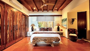 A bedroom with a bed, wooden wardrobe, bedside lamps, a chair, and a painting on the wall. - Waterfront Condo in Magnificent Manzanillo Bay Troncones (Troncones)