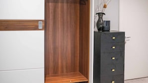 Un dressing accessible sans porte, avec une armoire en bois et une commode noire à tiroirs.