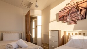 Ett hotellrum med två sängar, en garderob, ett skrivbord och en stor tavla på väggen.