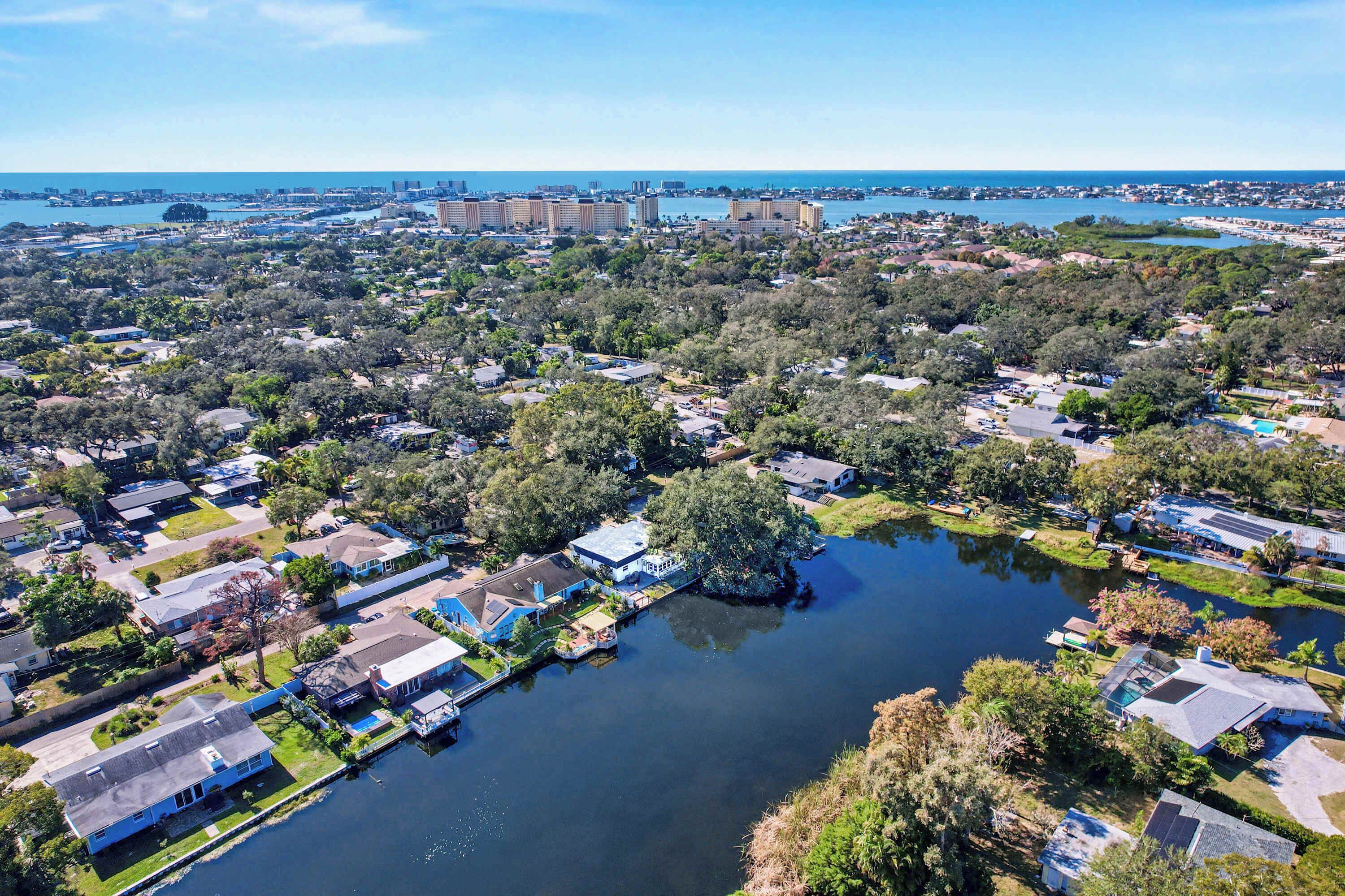 Vue aérienne d’un quartier résidentiel avec des maisons, un lac et des bâtiments situés au loin.