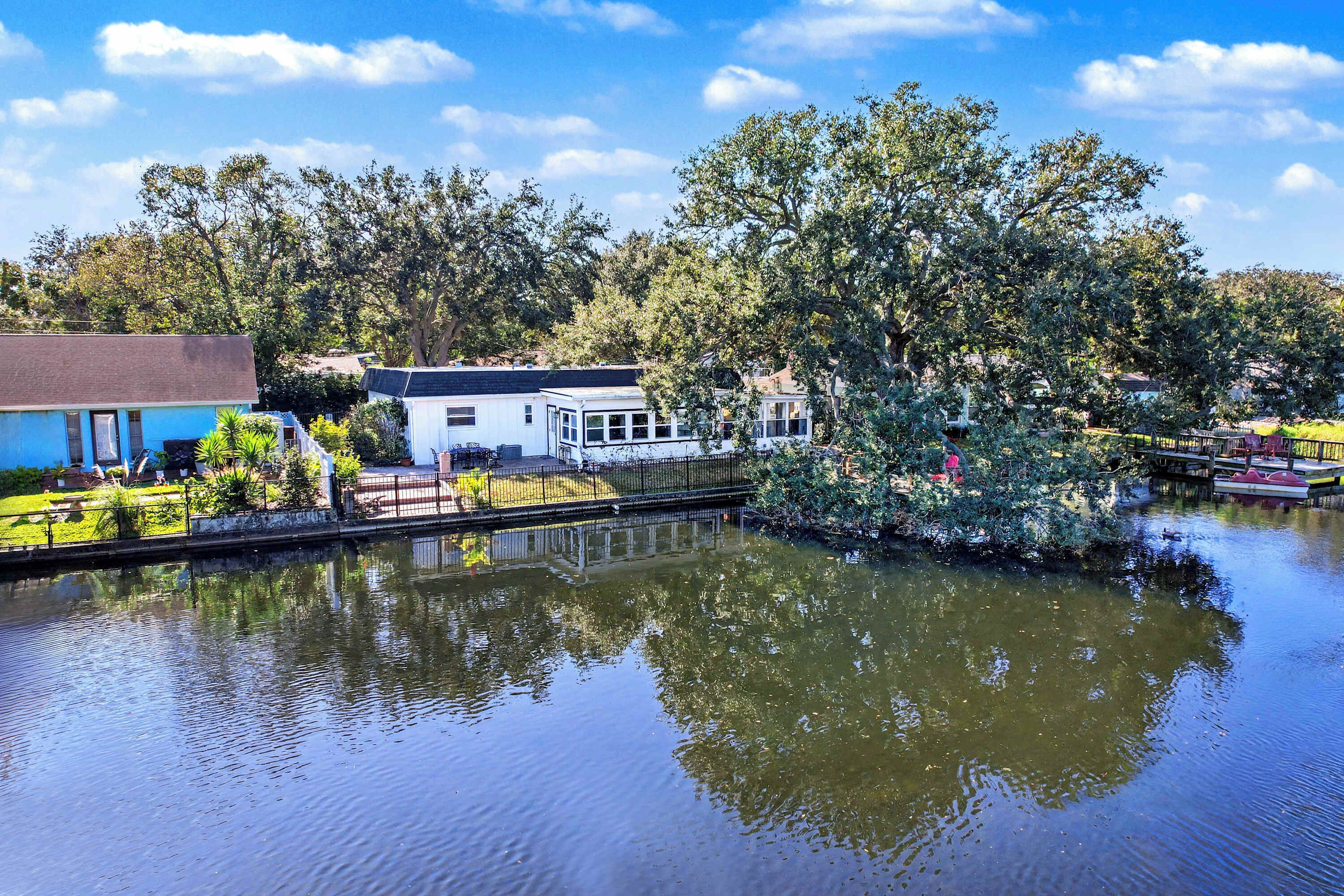 Una propiedad junto al río con una casa, un muelle y un bote pequeño.