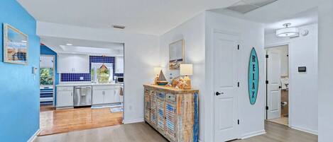 Una cocina moderna con armarios blancos, suelo de madera y una pared azul de acento.